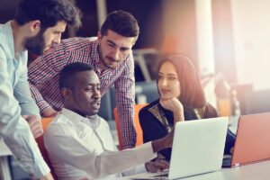 A group of professionals gathered around a laptop