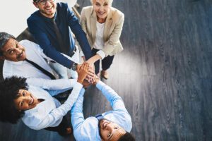 People arranged in a half-circle with their hands stacked on top of each others