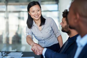 A professional woman shaking hands with a professional man
